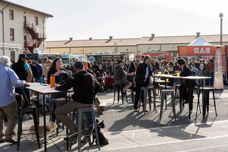 A crowd of people gather to eat at food trucks during Off the Grid at Fort Mason Center.